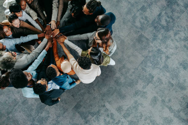 A diverse group of professionals joining hands in unity, symbolising strong corporate governance and the teamwork needed to manage director changes in Japan effectively and transparently.