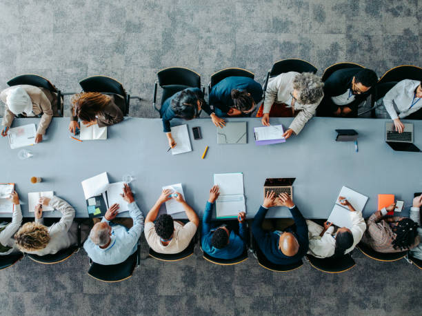 A group of professionals seated around a long conference table, representing a corporate board meeting discussing Annual General Meeting requirements and compliance in Canada.