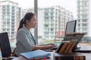 A woman using Company Secretarial Software on a laptop to manage director changes in Singapore.