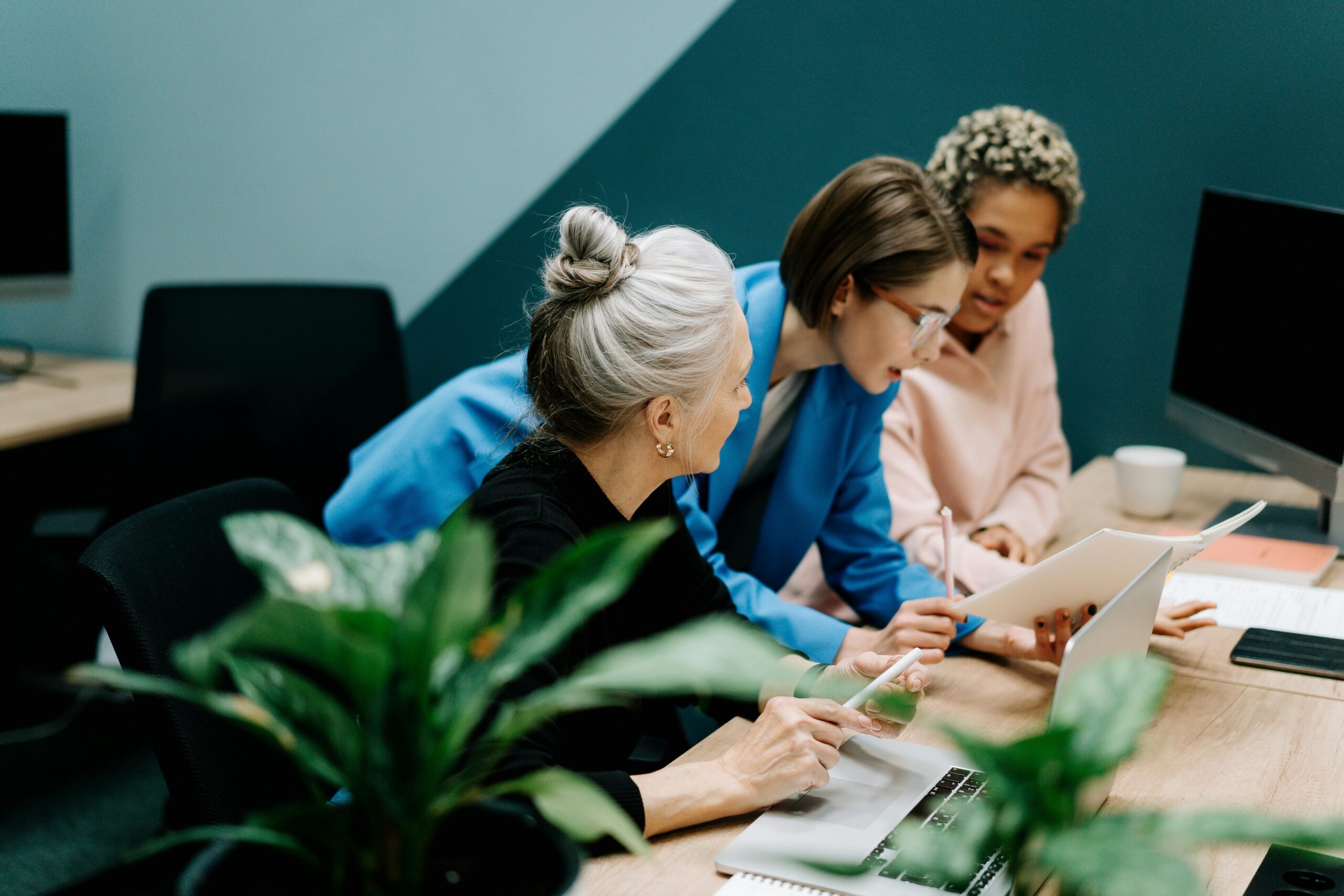 Three professionals collaborating at a desk while reviewing documents, representing the procedural teamwork behind officer changes for companies in Denmark.