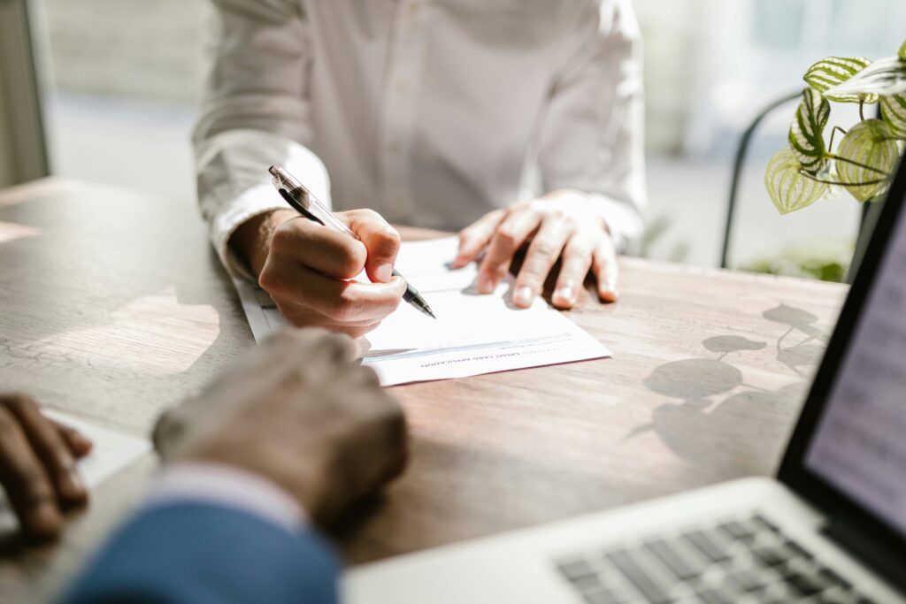A professional signing official documents at a bright office desk—capturing the formality and precision required when appointing or removing a company director in Sweden.