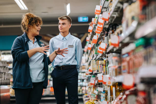 Two retail employees stand in a supermarket aisle discussing product organisation, symbolising how Danish businesses adapt operations and internal systems to new DB25 industry classifications under NACE Rev. 2.1.